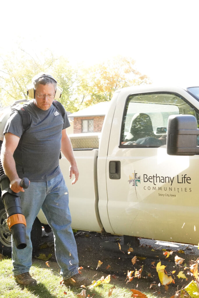 Handyman blowing leaves in front of a Bethany Life communities truck