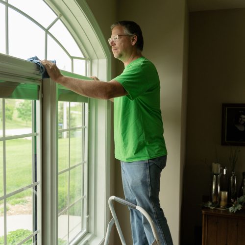 Handyman dusting the top of a window sill