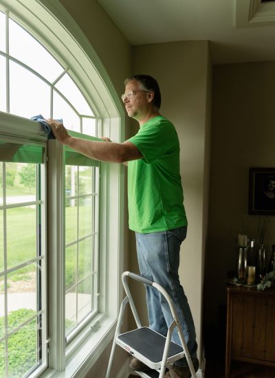 Handyman dusting top of a window