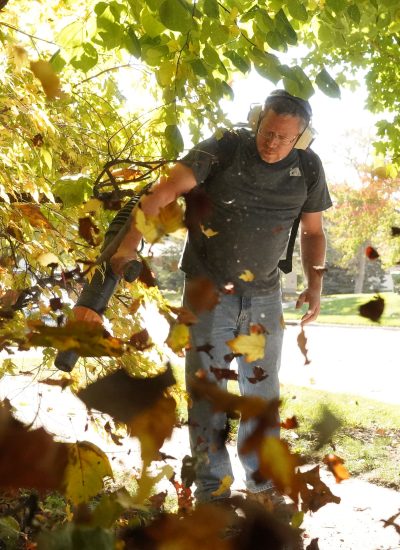 Handyman blowing leaves off a sidewalk