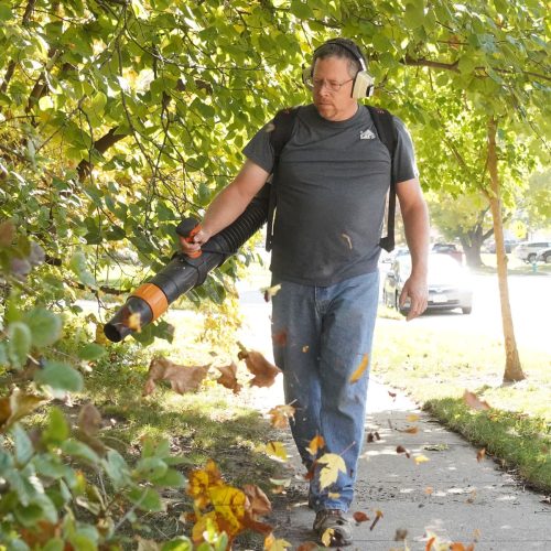 Handyman blowing leaves off a sidewalk