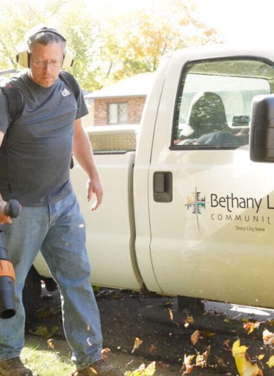 Handyman blowing leaves in front of a Bethany Life communities truck