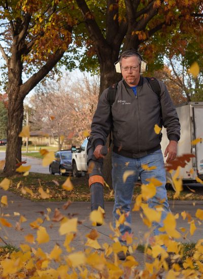 Handyman blowing leaves off of a sidewalk and driveway